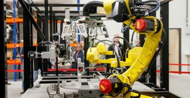 Žuti industrijski roboti rade u proizvodnoj liniji s dijelovima na pokretnoj traci