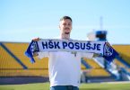 Igrač u dresу HŠK Posušje drži šal kluba na stadionu