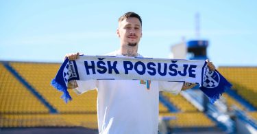 Igrač u dresу HŠK Posušje drži šal kluba na stadionu