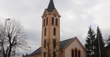 Katolička crkva s crvenom fasadom i crnim tornjem, oznaka mržnje na zidu