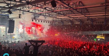 Masovna publika sa crvenim svjetlosnim efektima tokom rock koncerta u velikoj dvorani