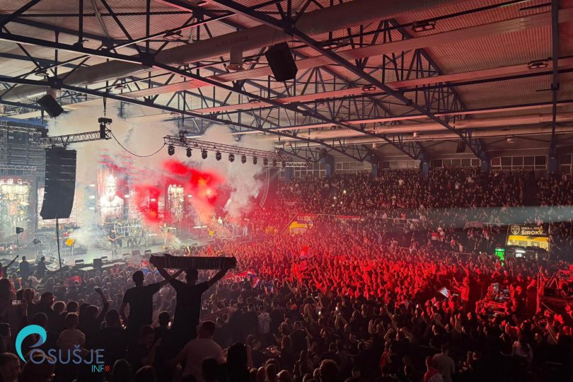 Masovna publika sa crvenim svjetlosnim efektima tokom rock koncerta u velikoj dvorani