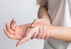 Žena drži zapešće i pokazuje bol ili nelagodu u ruci