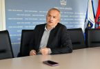 Muž u poslovnom odijelu za stolom tijekom saslušanja