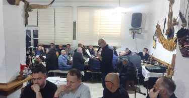Publika sluša nastup tradicijske glazbe u dvorani, guslarci i glazbenici izvode na pozornici