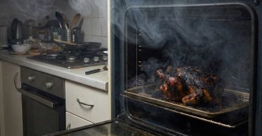 Zagorjela hrana u pećnici s vidljivo crnim naslaga i dim