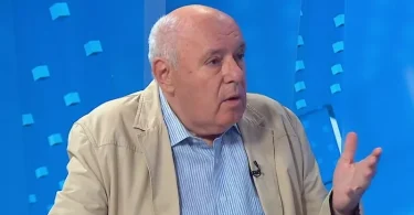 Muž u svjetloj jakni govori o politici i himni tijekom TV intervjua