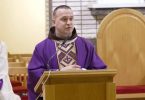 Franjevac u purpurnoj liturgijskoj odjeći govori sa propovjedaonice u crkvi