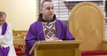 Franjevac u purpurnoj liturgijskoj odjeći govori sa propovjedaonice u crkvi