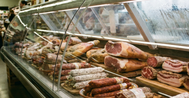 Različiti suhomesnati proizvodi izloženi u hladnjači mesnice ili supermarketa