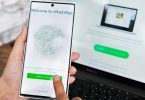 Korisnik drži pametni telefon s WhatsApp Web sučeljem na zaslonu i biometrijskom autentifikacijom
