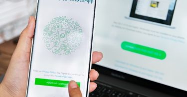 Korisnik drži pametni telefon s WhatsApp Web sučeljem na zaslonu i biometrijskom autentifikacijom