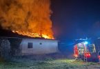 Kuća u plamenu noću s vatrogasnim vozilom u stanju spašavanja