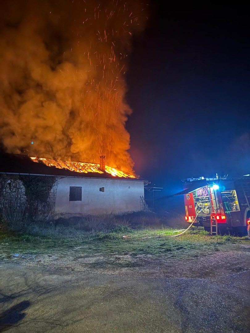 Kuća u plamenu noću s vatrogasnim vozilom u stanju spašavanja