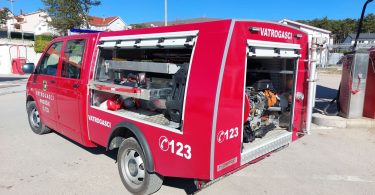Crveno vatrogasno vozilo broja C123 s otvorenim vratima i opremom vidljiva na terenu