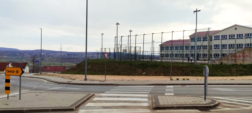 Sportski teren i parkiralište ispred osnovne škole sa modernom oplatom i svjetlosnom infrastrukturom