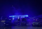 Noćna fotografija više izgorjelih automobila na školskom dvorištu s vozilima hitne pomoći i policije