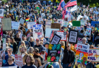 Velika masa demonstranata na ulici s plakatima i američkim zastavama tijekom prosvjeda