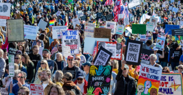 Velika masa demonstranata na ulici s plakatima i američkim zastavama tijekom prosvjeda