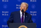 Američki predsjedenik Trump govori pri postolju sa znakom Odbora za mir