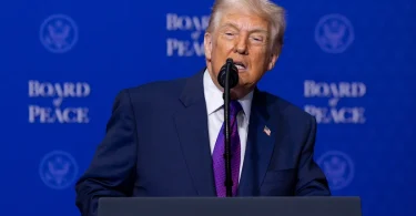 Američki predsjedenik Trump govori pri postolju sa znakom Odbora za mir