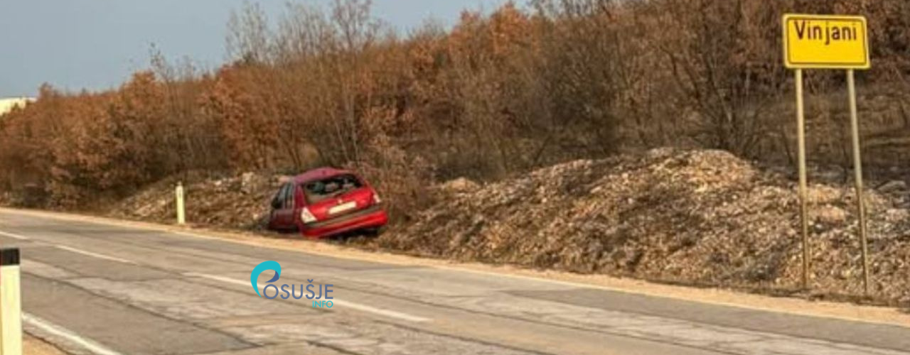 Oštećeni crveni automobil na prometnoj traci pored znaka Vinjani