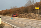 Oštećeni crveni automobil na prometnoj traci pored znaka Vinjani
