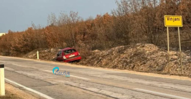 Oštećeni crveni automobil na prometnoj traci pored znaka Vinjani