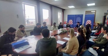 Grupa sudionika programa prekvalifikacije medicinskih sestara/tehničara sjedи za stolom tijekom potpisivanja ugovora u Grudama