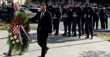 Policijski službenici polažu cvijeće kod spomen-obilježja tijekom službene ceremonije