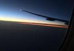 Pogled kroz prozor zrakoplova s krilom tijekom zalaska sunca nad horizontom