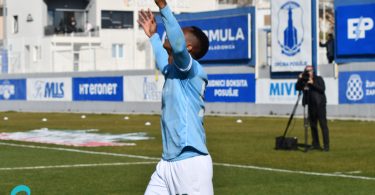 Nogometaš u plavoj majici Posušja izvodi skok i slavi gol na stadionu