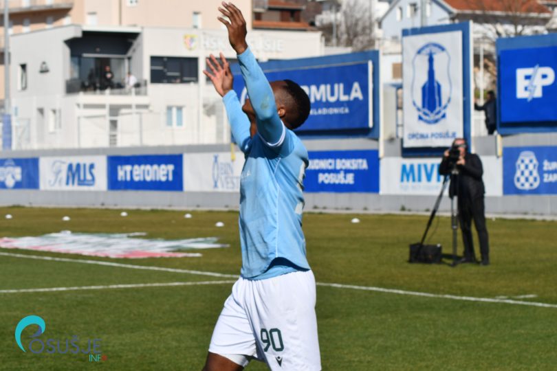 Nogometaš u plavoj majici Posušja izvodi skok i slavi gol na stadionu