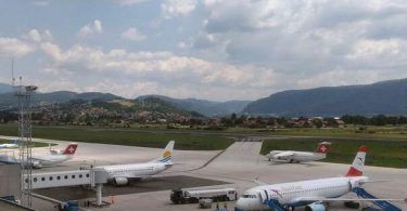 Putnički avioni na aerodromu Sarajevo s pistom i planinama u pozadini