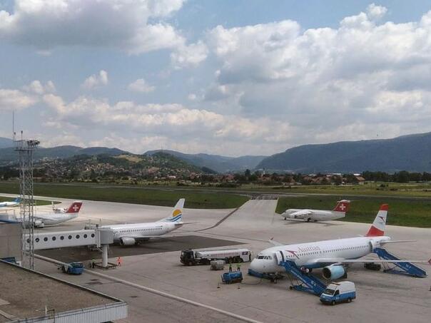 Putnički avioni na aerodromu Sarajevo s pistom i planinama u pozadini