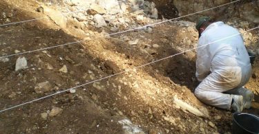 Radnik u bijeloj majici tijekom ekshumacije, snimanje terenske dokumentacije