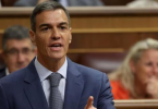 Muškarac u tamnom odijelu i plavoj kravati govori u parlamentu