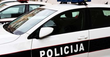 Bijelo-plava policijska vozila s uključenim rotacijskim svjetlima na cesti