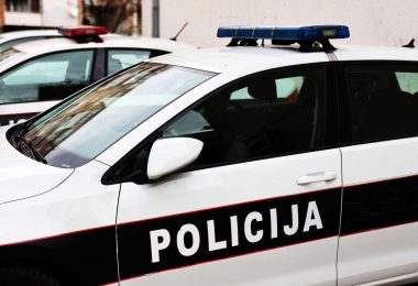 Bijelo-plava policijska vozila s uključenim rotacijskim svjetlima na cesti