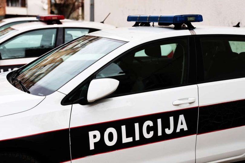 Bijelo-plava policijska vozila s uključenim rotacijskim svjetlima na cesti