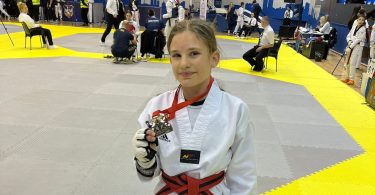 Judašica u bijelom kimonoju s crvenim pojasom i bronznom medaljom