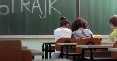 Učenici sjede u učionici s natpisom štrajk na pločи tijekom štrajka upozorenja