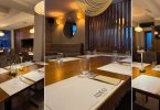 Elegantna blagovaonica restorana s drvenim detaljima, osvjetljenim stolicama i profesionalnim postavljanjem stolova