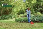 Čovjek čisti travnjak grabnjem i uklanja mrtvuš sa zelene površine