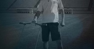 Portret muškarca u bijeloj majici na stadionu s godinama 1959 - 2026