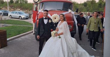 Mladenci u vjenčanoj odjeći pred vatrogasnim kamionom sa svatovima