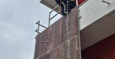 Vatrogasac u uniformi spušta se užetom uz fasadu zgrade tijekom obuke