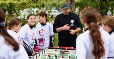 Mladi nogometaši u bijelim dresovima oko UEFA WU19 trofeja s trenerom tijekom edukativne aktivnosti