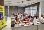 Grupa policajaca i građana sjedim za stolom tijekom javnog razgovora o sigurnosti.