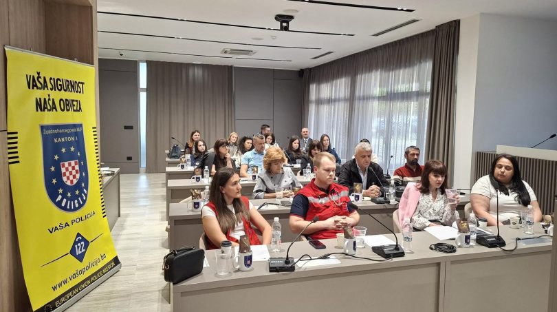Grupa policajaca i građana sjedim za stolom tijekom javnog razgovora o sigurnosti.